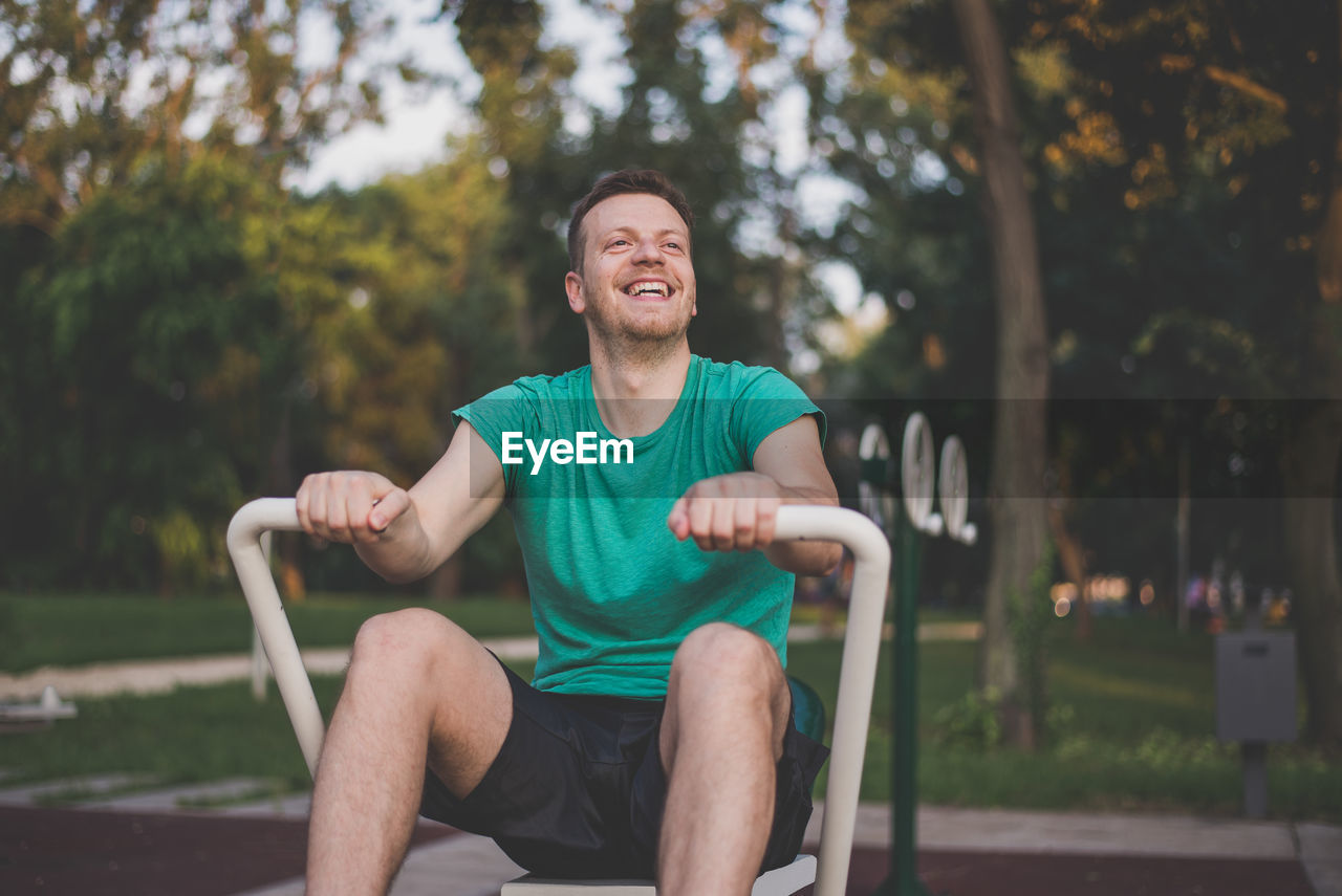 Man sitting on equipment while exercising in park