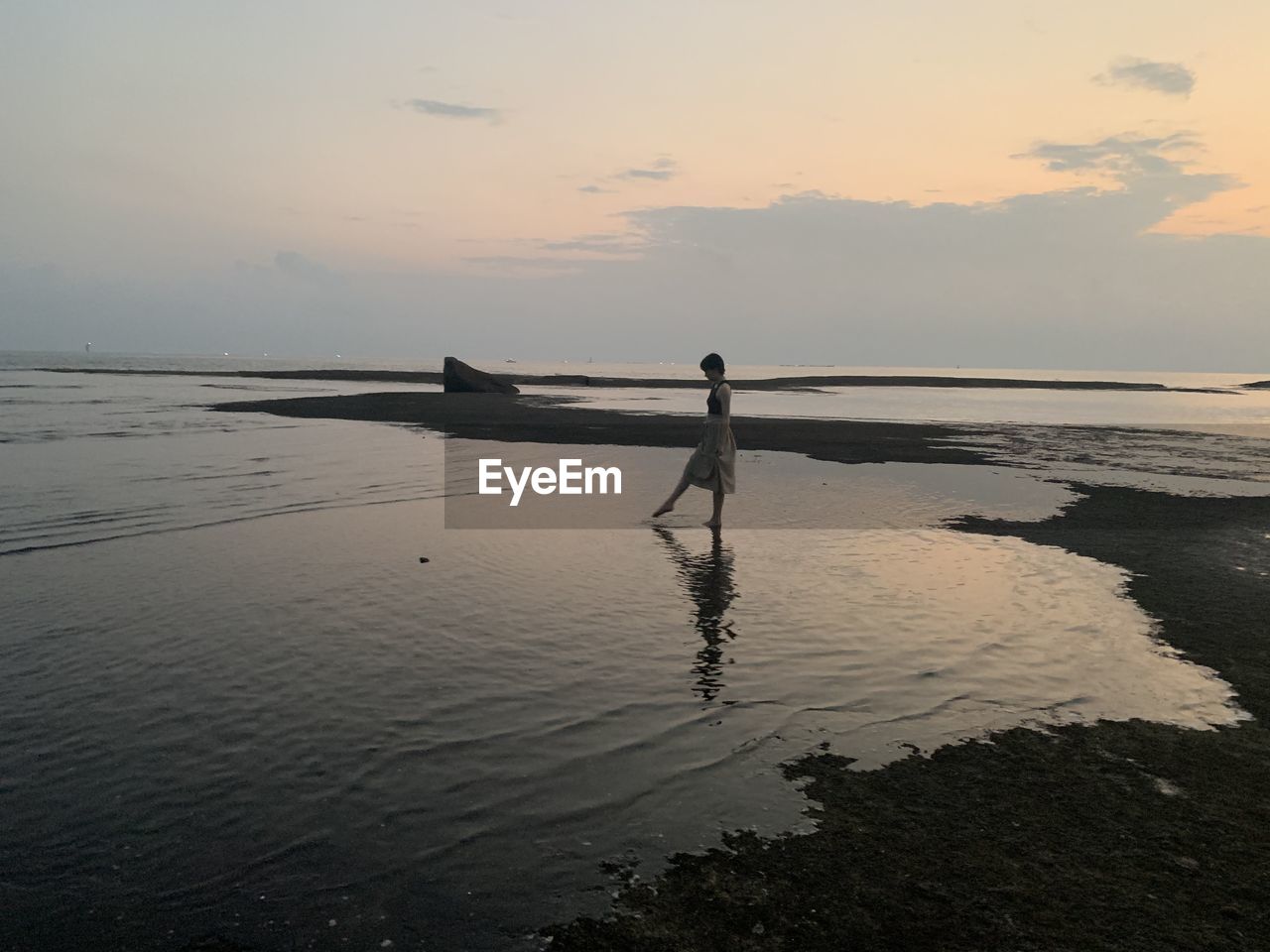 Silhouette person on beach against sky during sunset