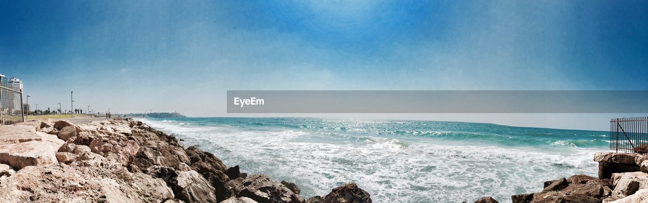 Scenic view of rock by seascape against blue sky