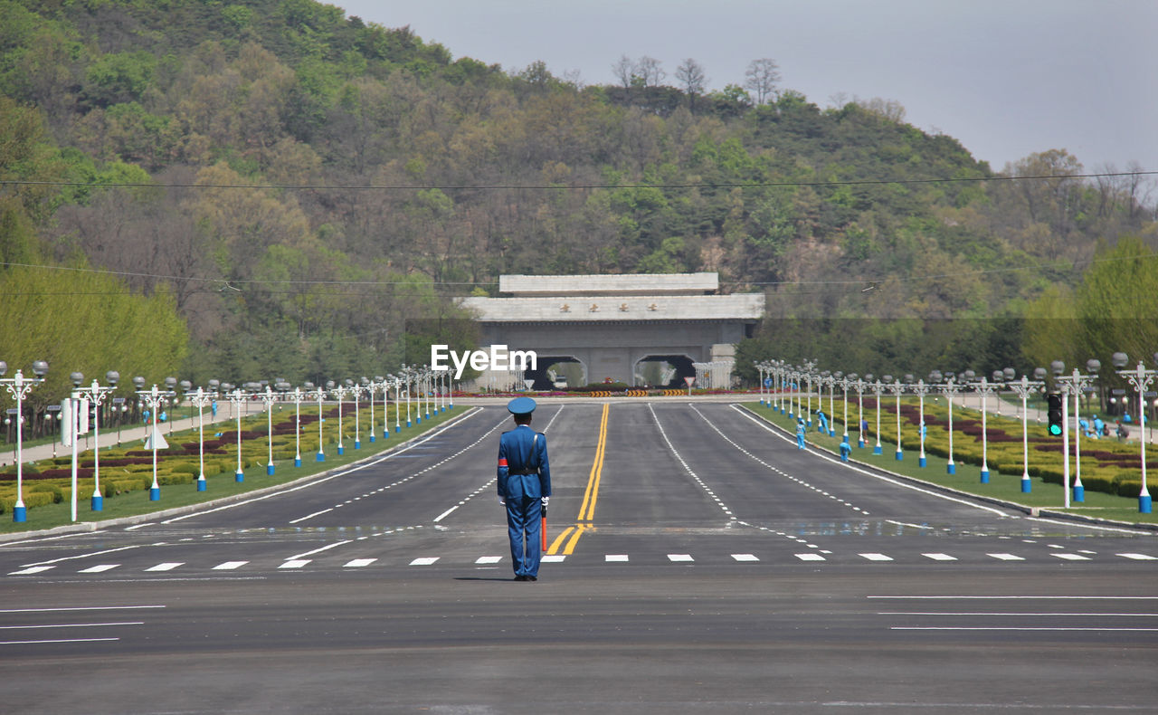 REAR VIEW OF MAN ON ROAD