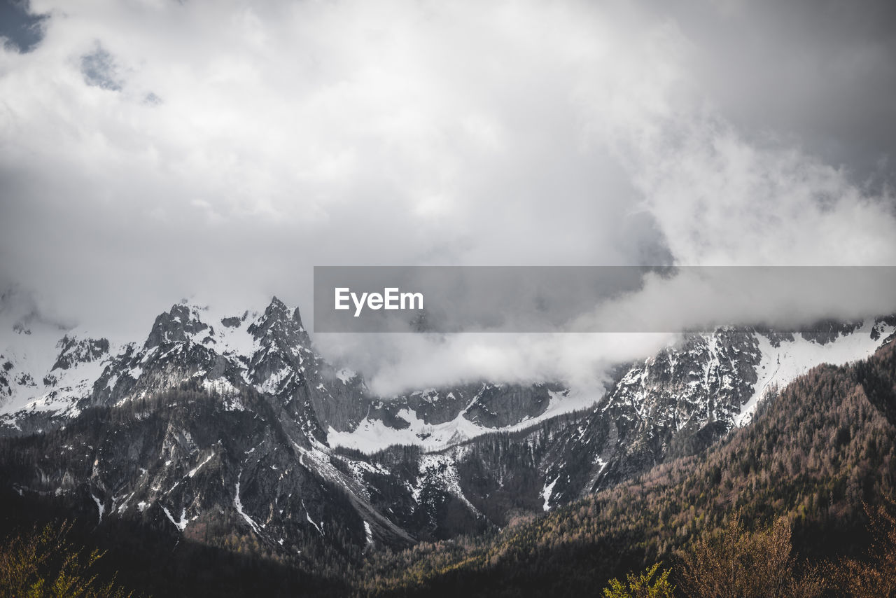 Scenic view of mountains against cloudy sky during winter