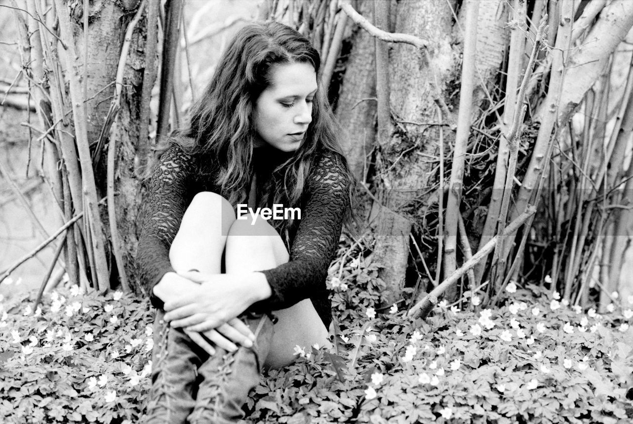 Young woman looking away while sitting on grassy field