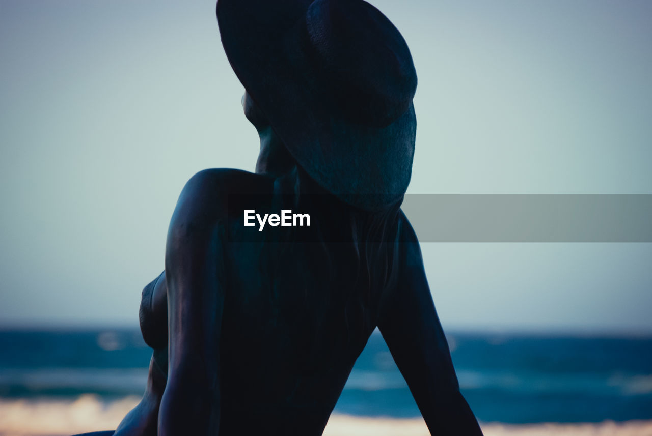 MAN STANDING AT BEACH AGAINST SKY