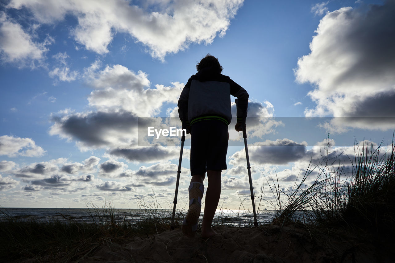 REAR VIEW OF MAN STANDING ON SHORE