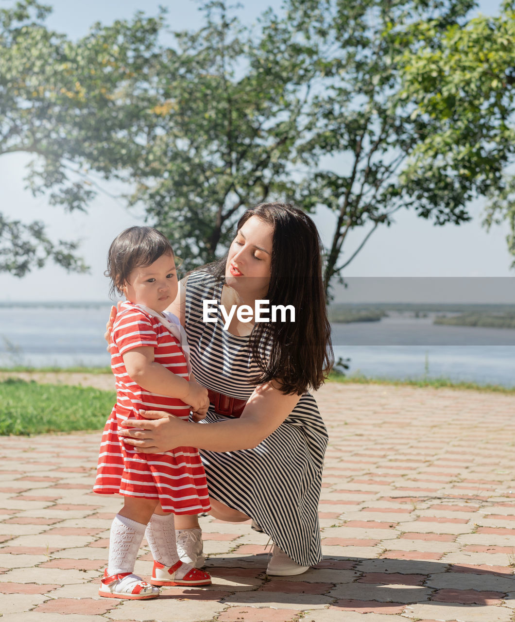 Mother and daughter on land against tree and river