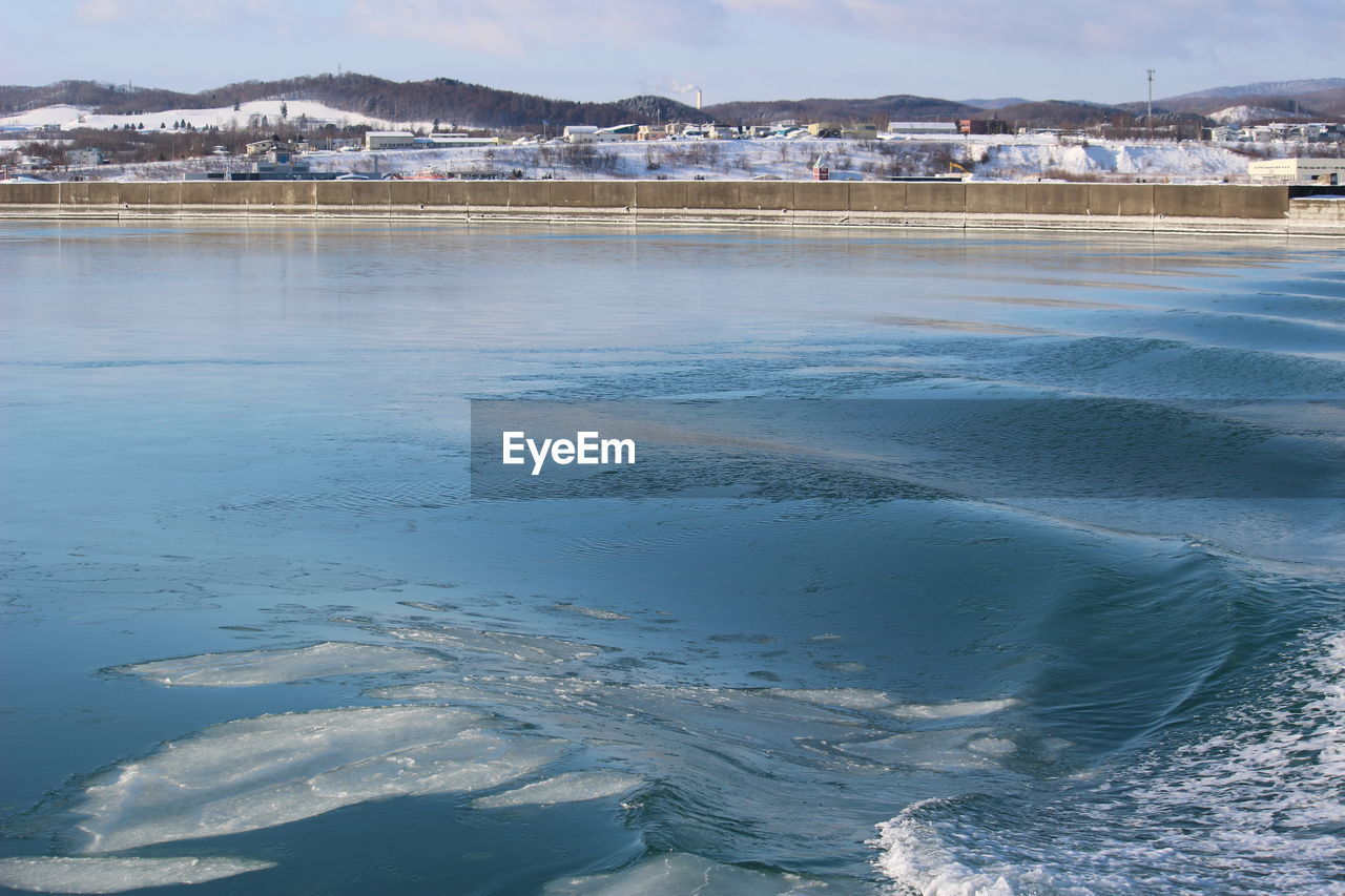 Scenic view of frozen lake against sky in city