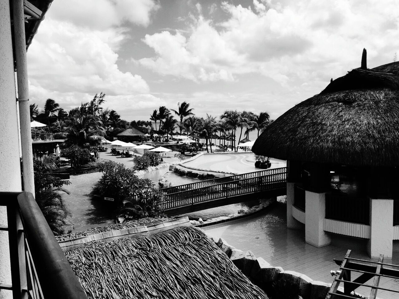 High angle view of gazebo and palm trees at resort against cloudy sky