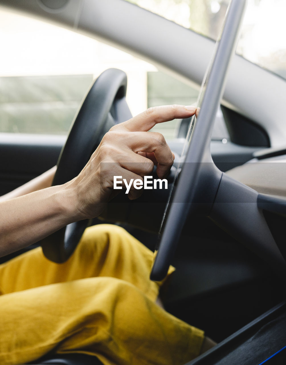 Woman using digital tablet while driving electric car