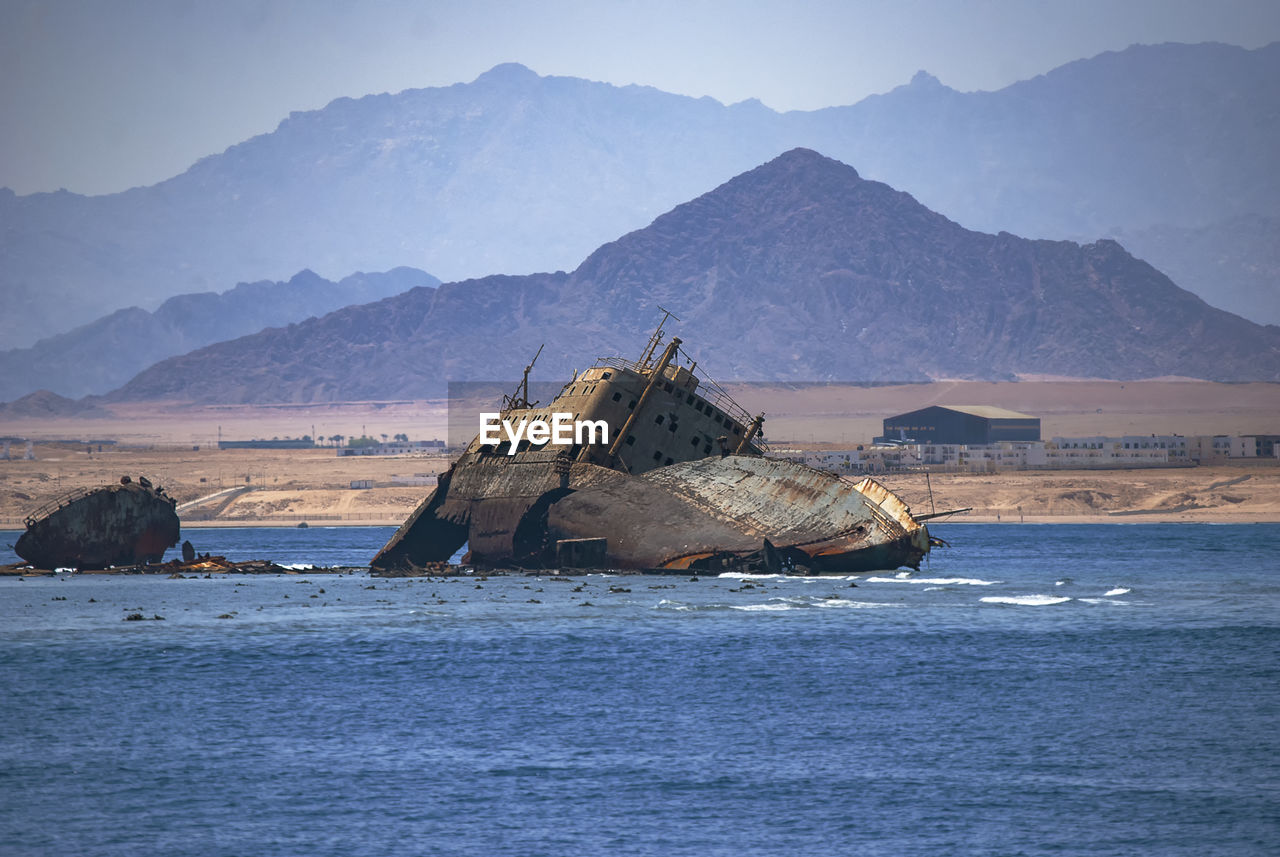 Shipwreck in sea against mountains