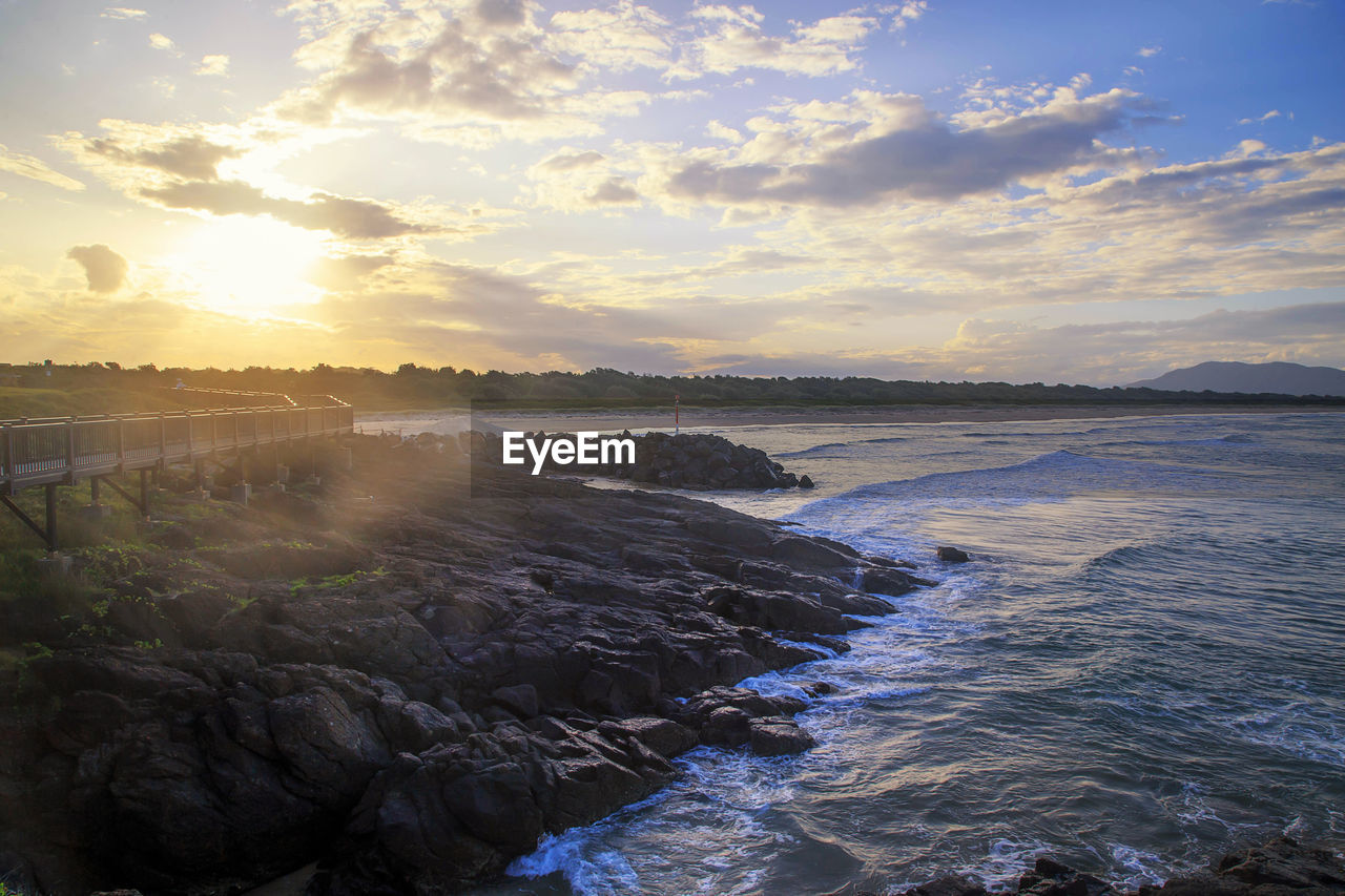 sky, water, sea, sunset, beauty in nature, land, scenics - nature, ocean, cloud, nature, wave, coast, shore, body of water, environment, landscape, horizon, sun, dawn, beach, rock, wind wave, sunlight, travel destinations, travel, evening, tranquility, no people, outdoors, reflection, seascape, coastline, tranquil scene, motion, blue, sports, tourism, idyllic, summer, trip, holiday, dramatic sky, sunbeam, vacation