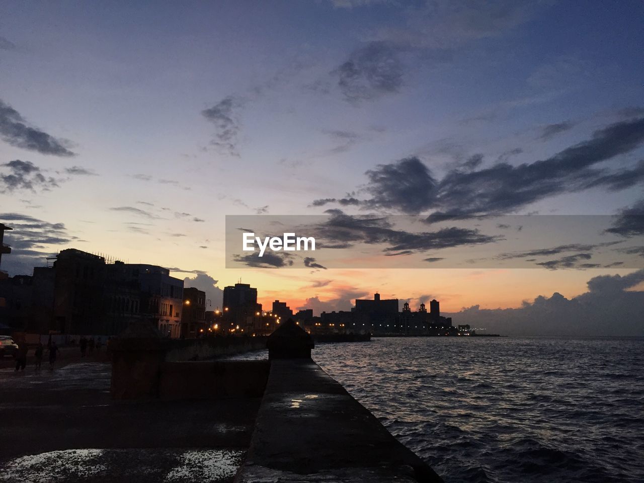 Scenic view of sea by city against sky during sunset