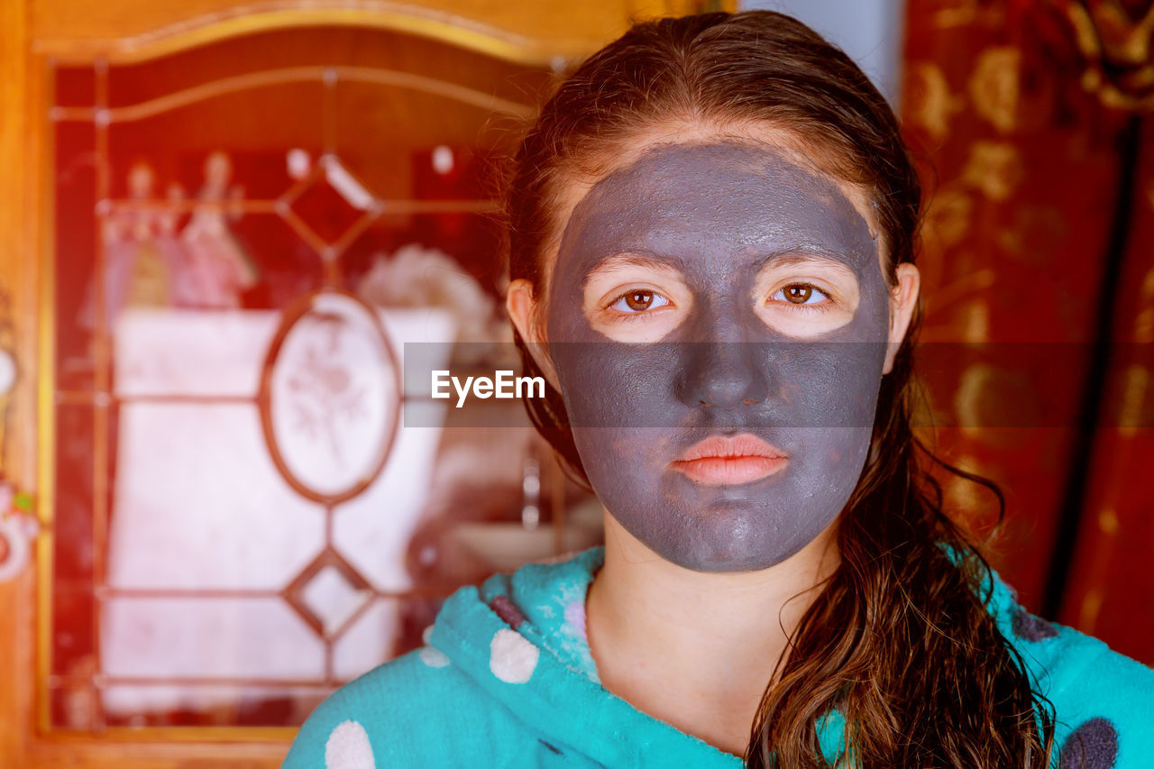 Close-up portrait of girl with facial mask at home