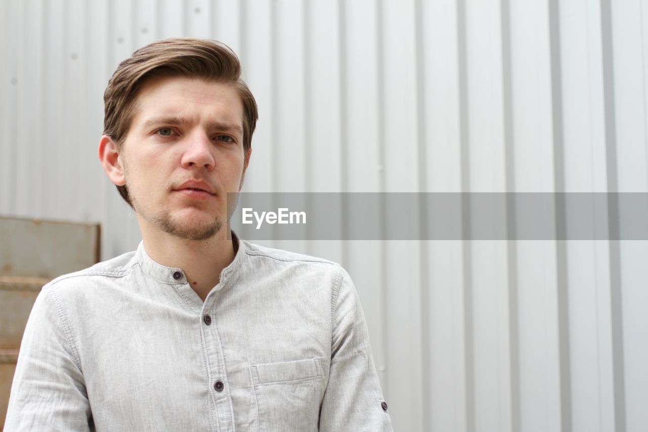 Portrait of handsome man standing against wall