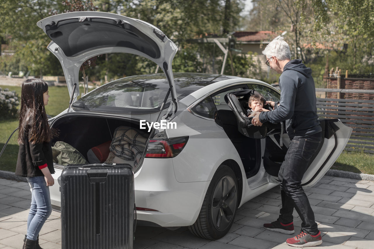 Man putting daughter into car