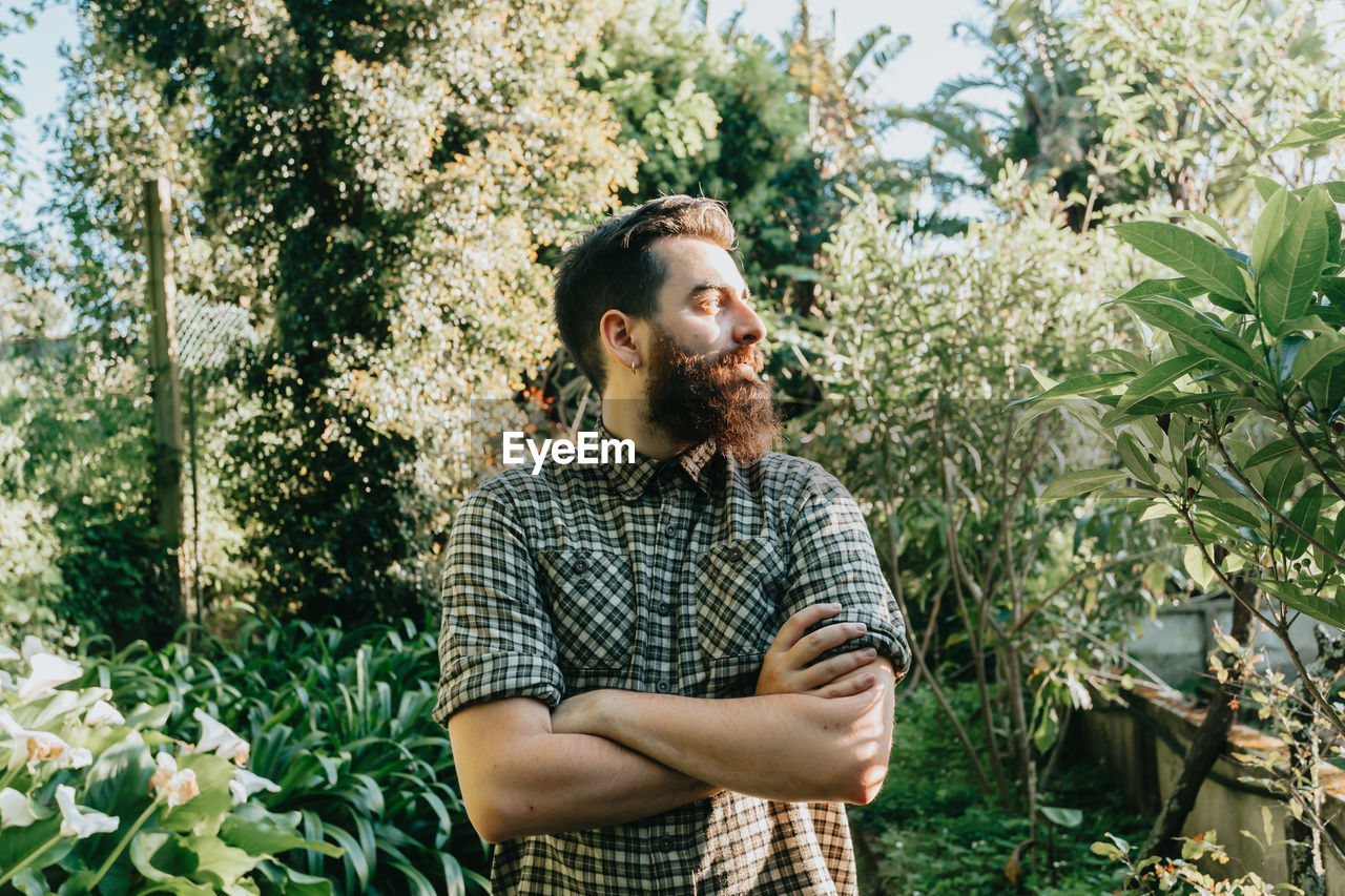 Young man standing against plants