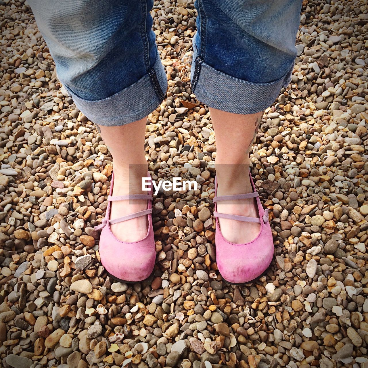 Low section of woman standing on pebbles