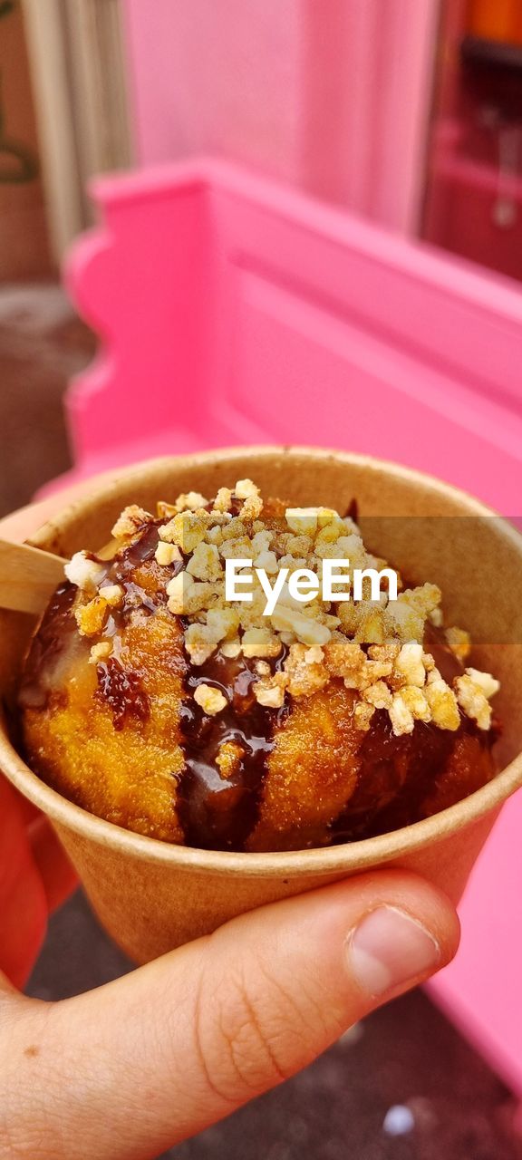 CLOSE-UP OF HAND HOLDING CAKE