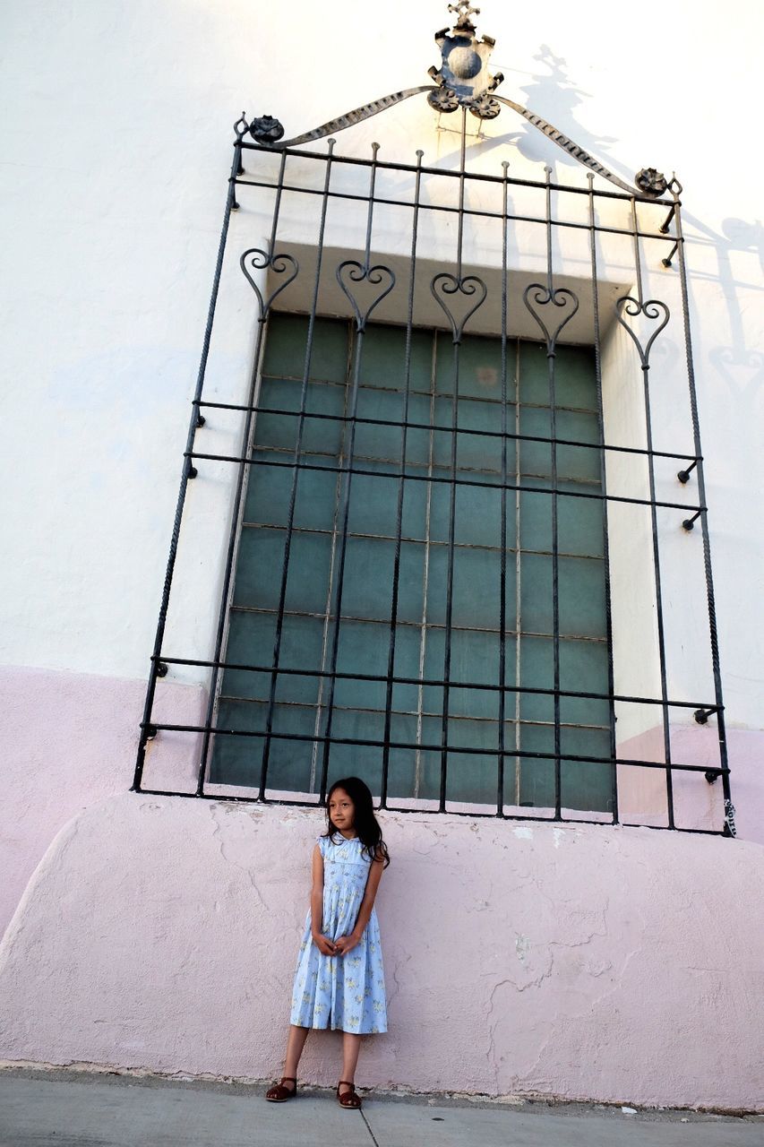 Tilt shot of girl standing against window