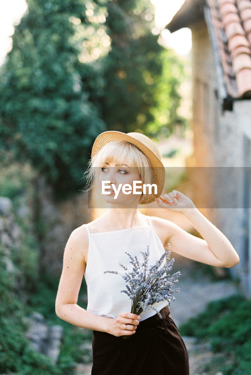 portrait of smiling young woman standing against plants