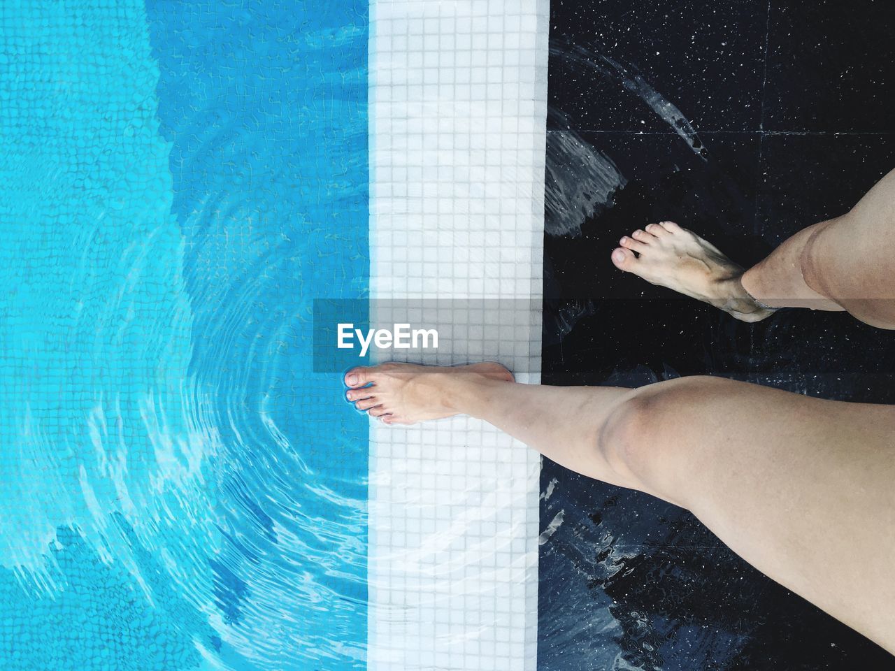 Low section of woman standing by swimming pool