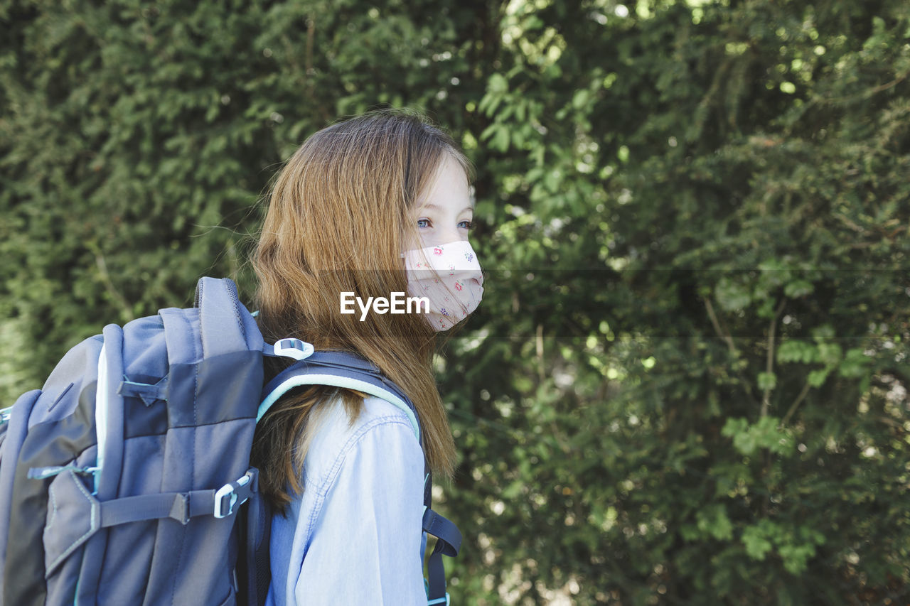 Girl wearing mask while standing with backpack