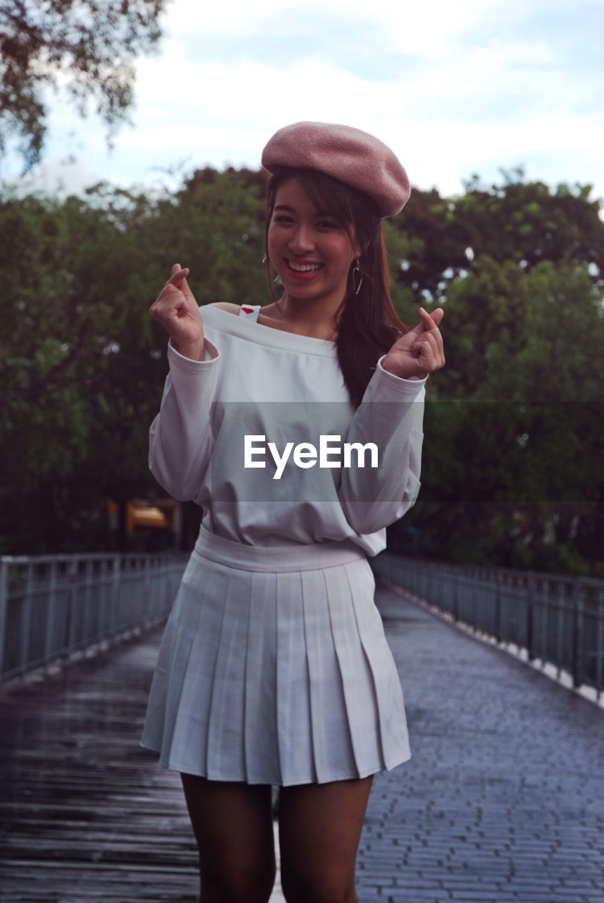 Portrait of happy young woman standing on footbridge