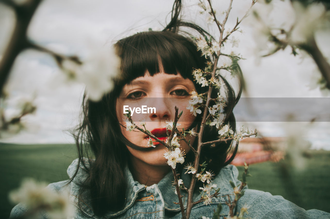 Portrait of young woman against plants