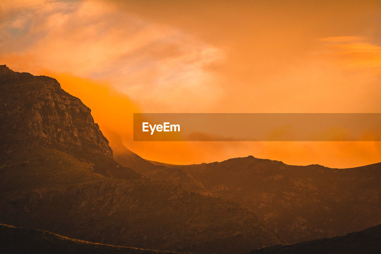 Scenic view of mountains against orange sky