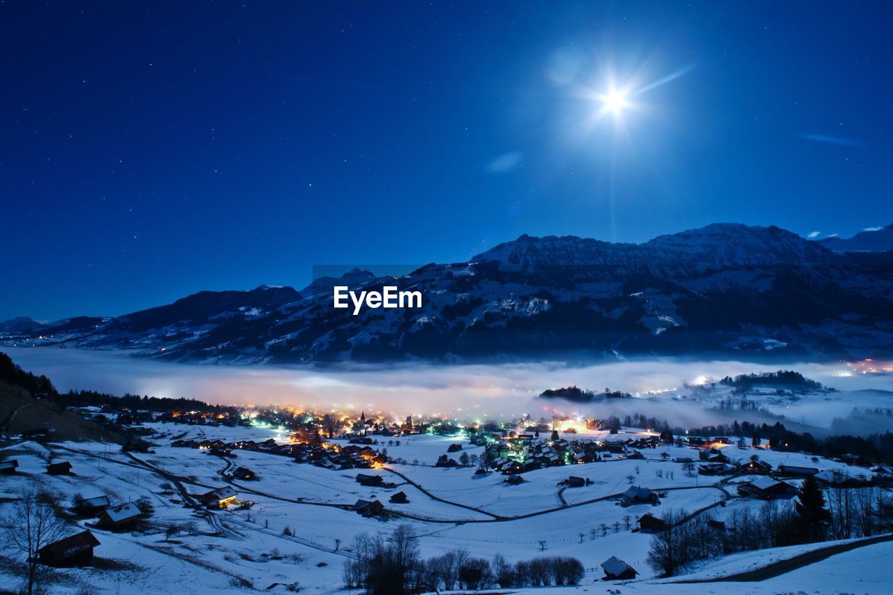 Scenic view of snowcapped mountains against blue sky at night