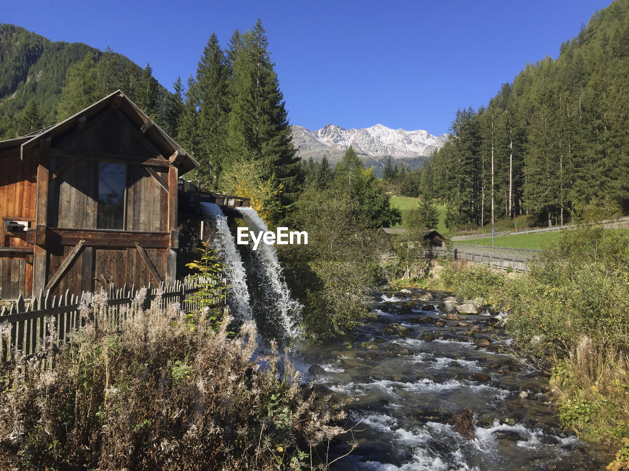 SCENIC VIEW OF WATERFALL BY TREES AGAINST SKY