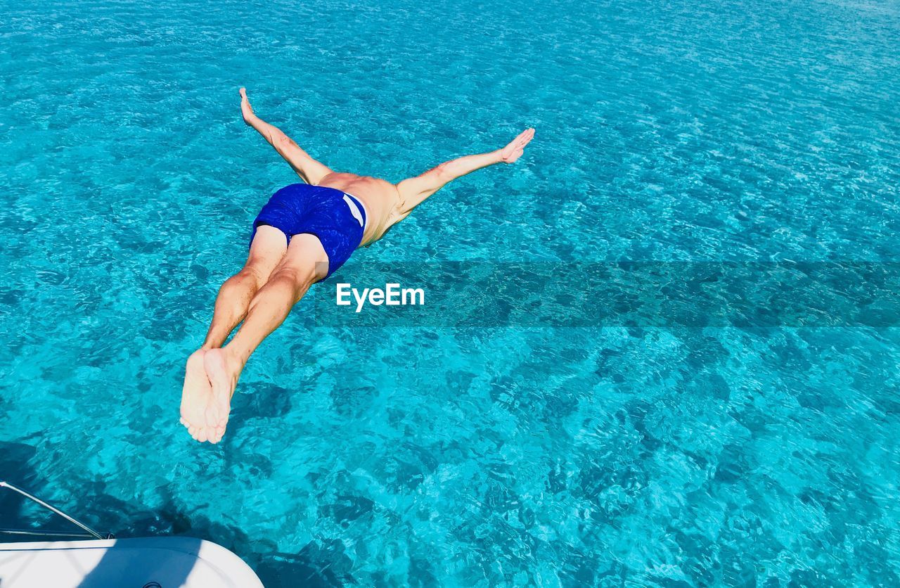 REAR VIEW OF WOMAN IN SWIMMING POOL