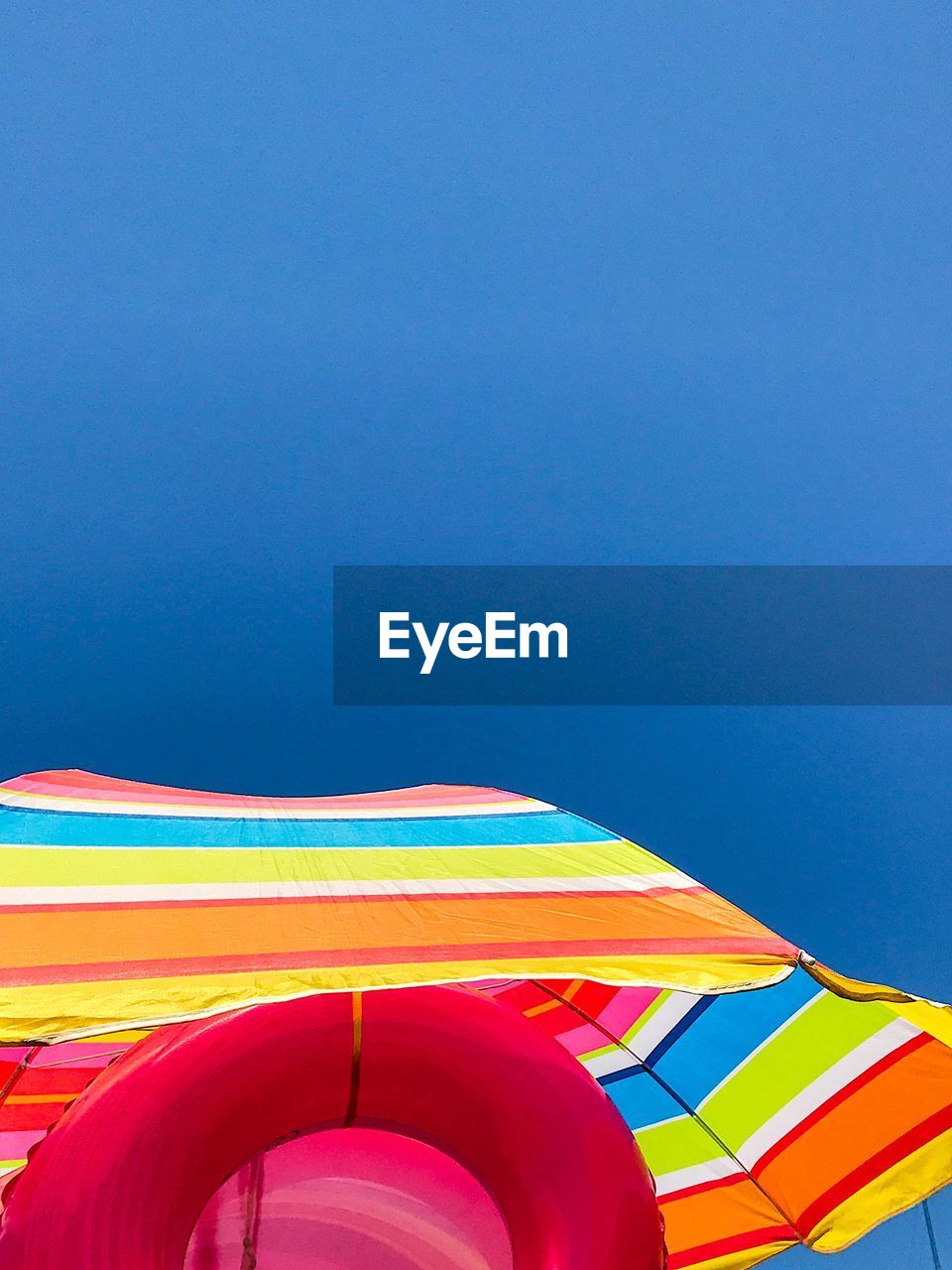 LOW ANGLE VIEW OF UMBRELLAS AGAINST CLEAR BLUE SKY