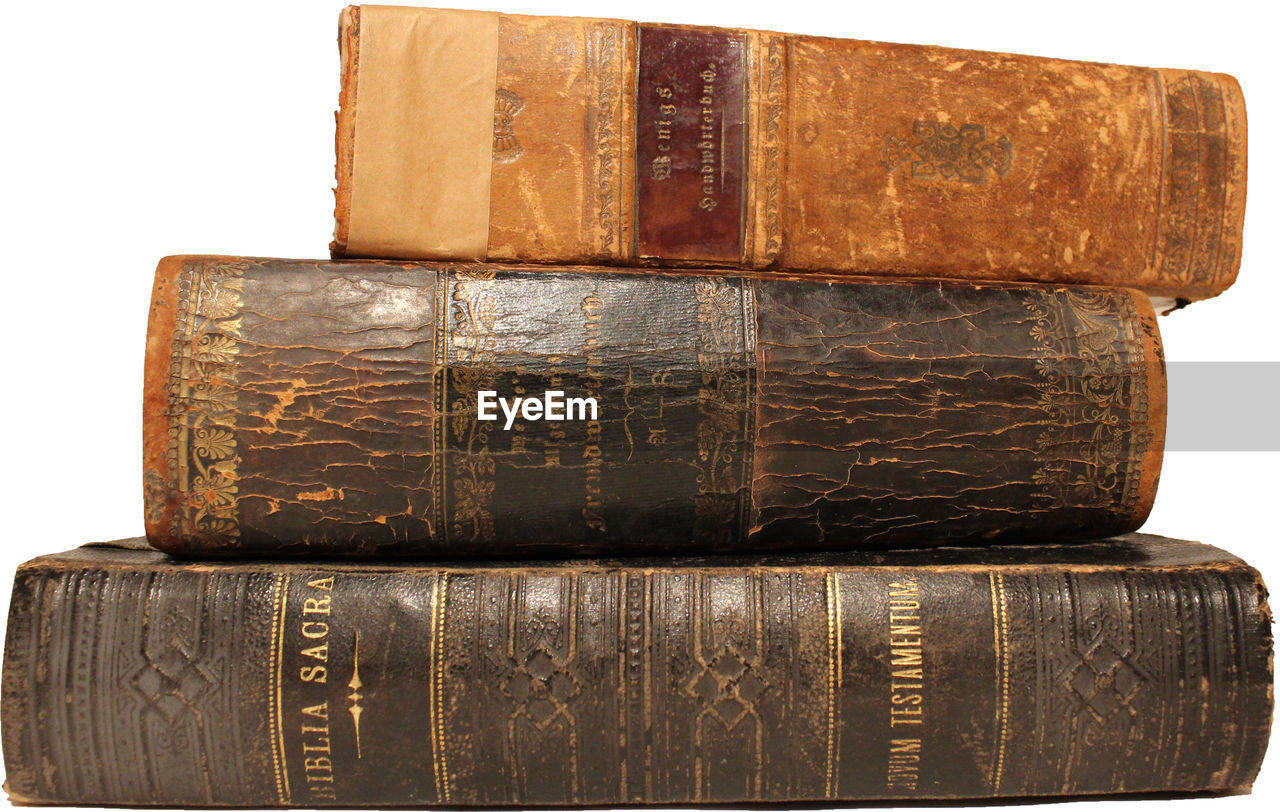 Close-up of old stacked books against white background