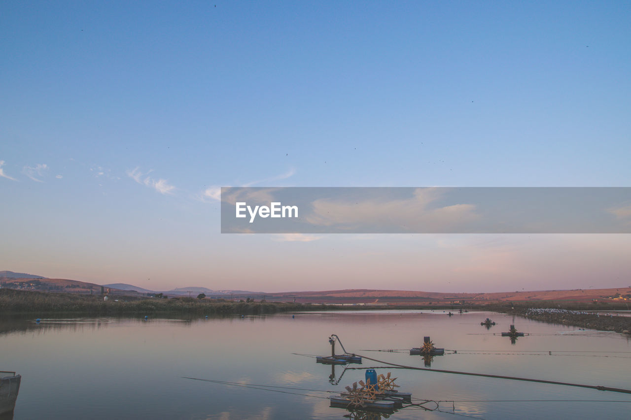 Boats sailing in sea against sky during sunset