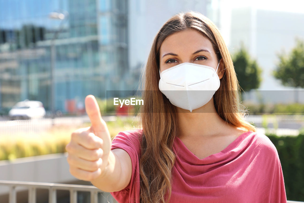 Portrait of young woman wearing flu mask holding file walking on road