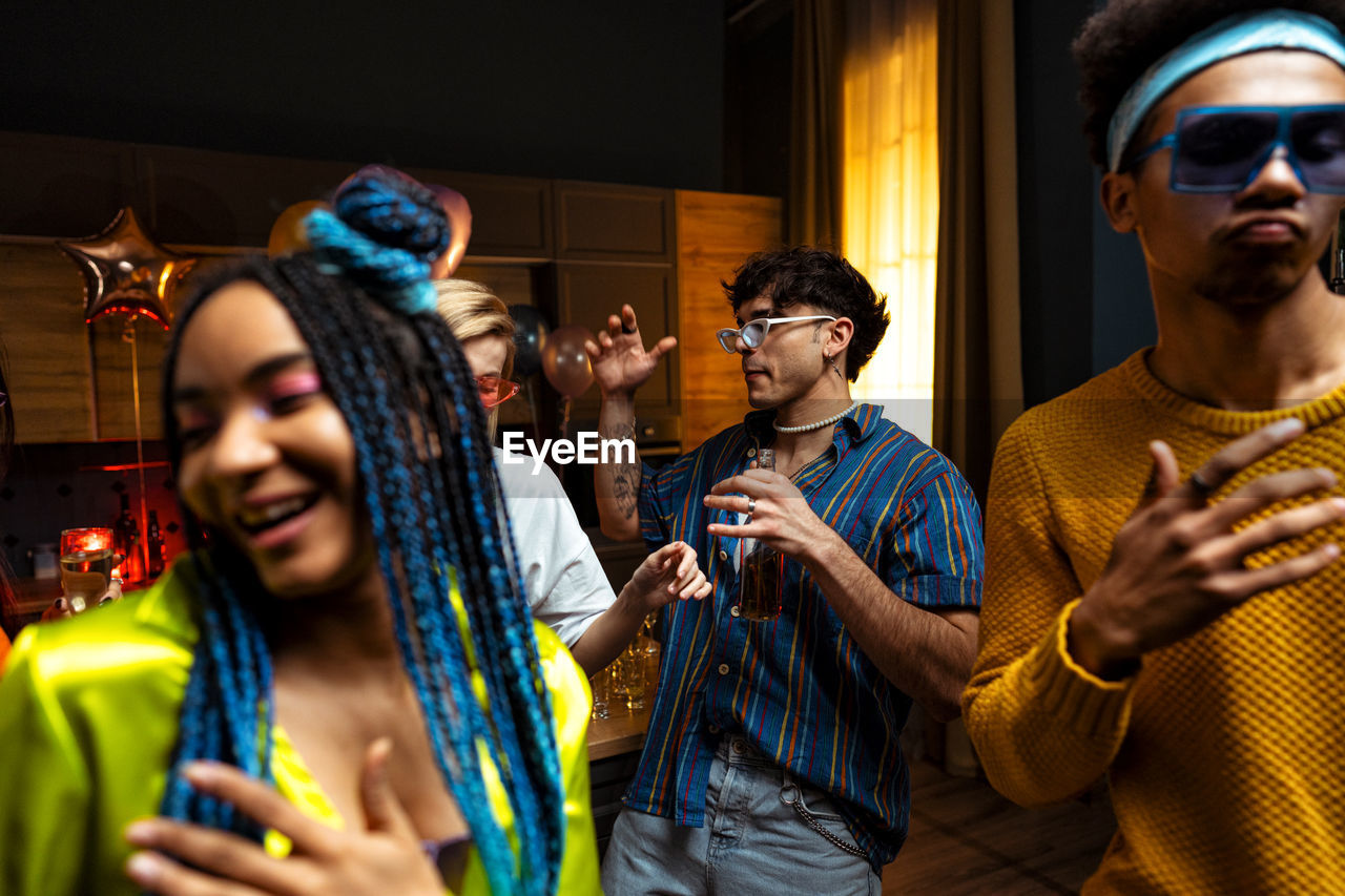 portrait of smiling friends with hands while standing at home