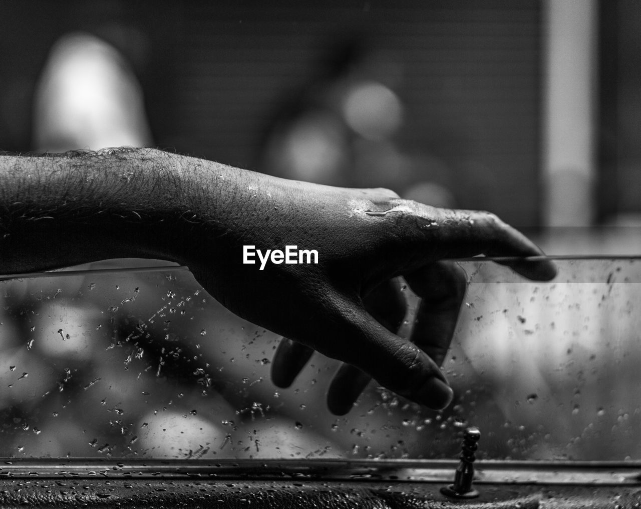 Cropped hand of man on wet car window