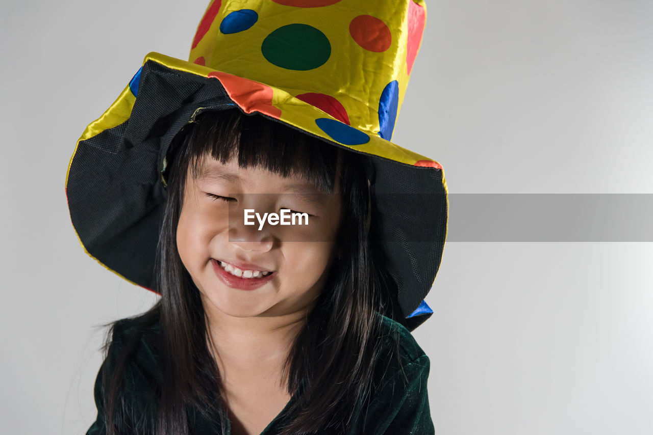 Close-up of girl wearing party hat against white background