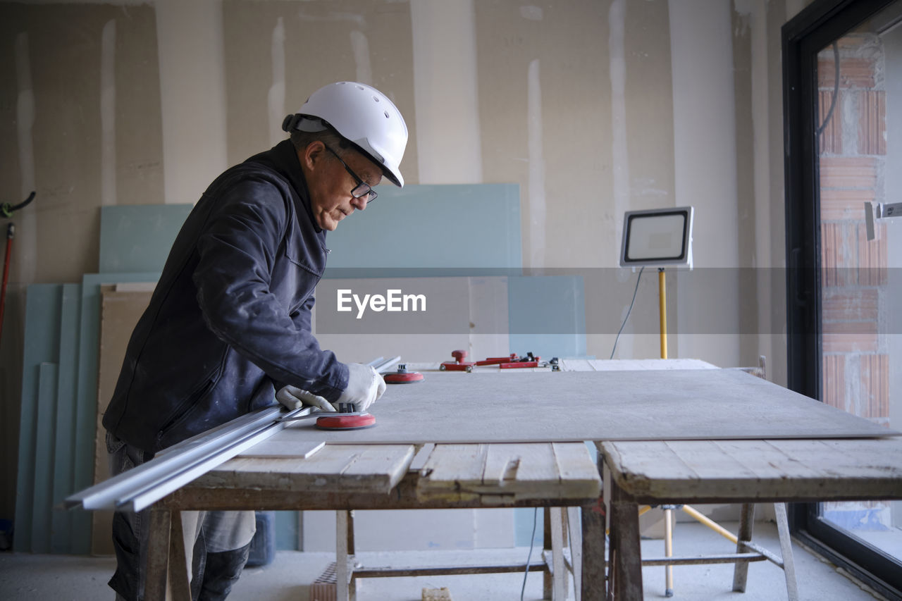 Construction worker with sheetrock on workbench at site