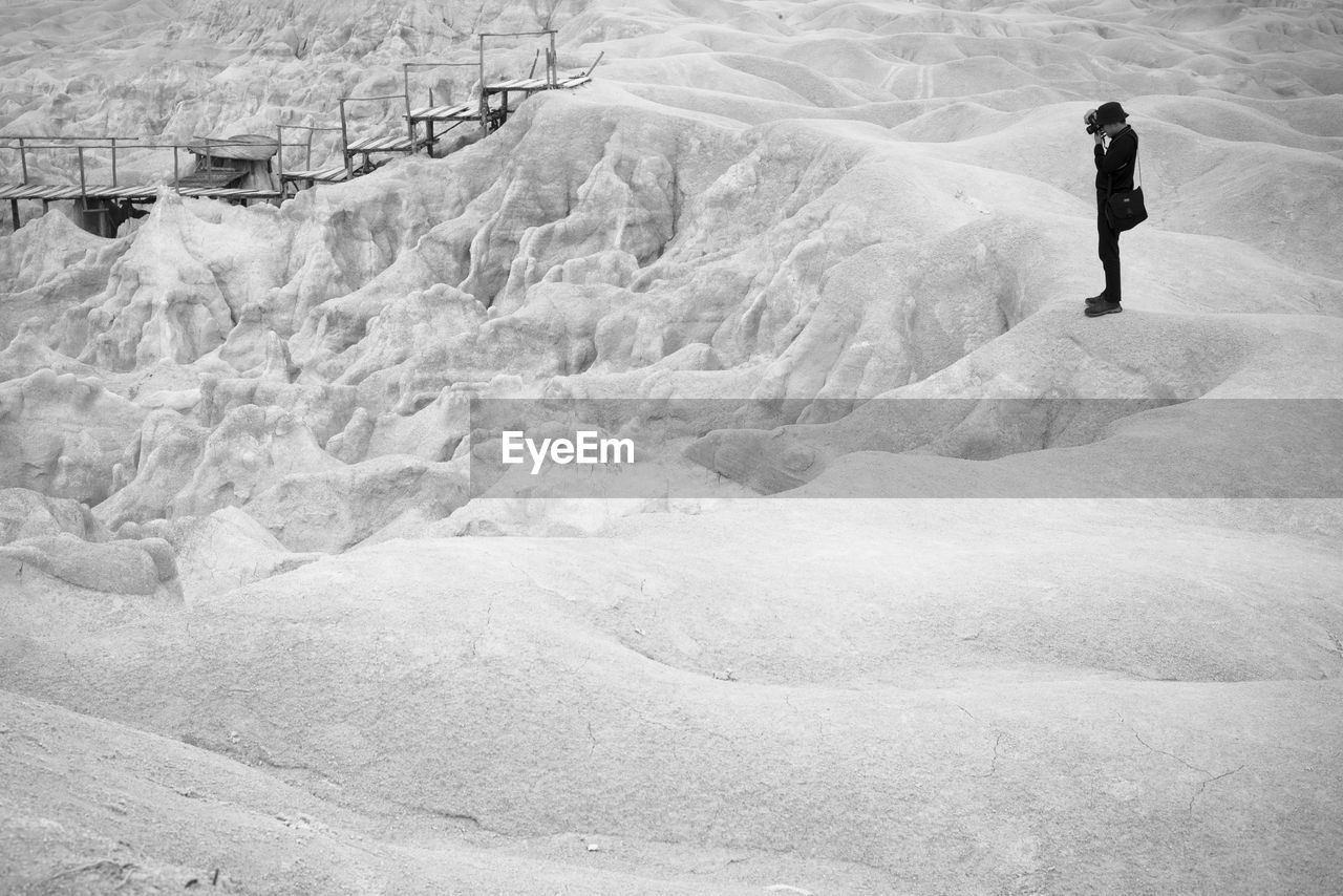 REAR VIEW OF MAN STANDING ON SNOW