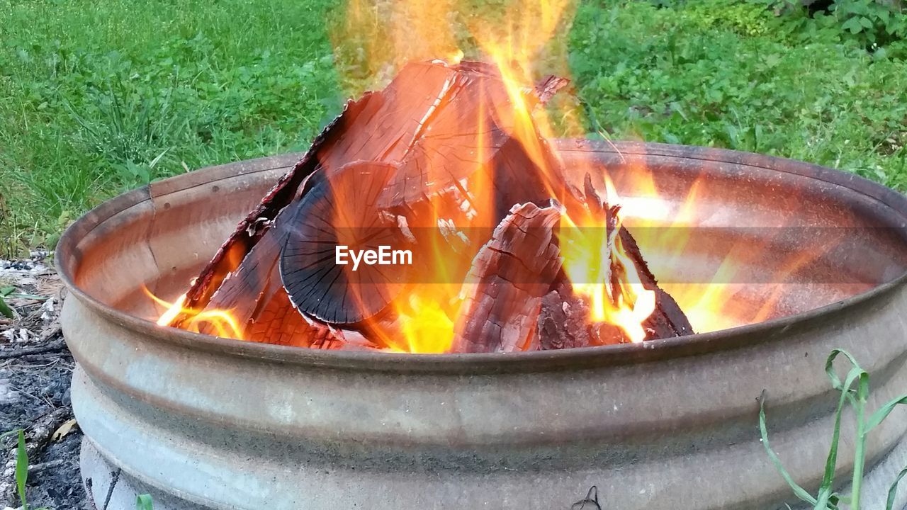 Close-up of wood burning in fire pit on field