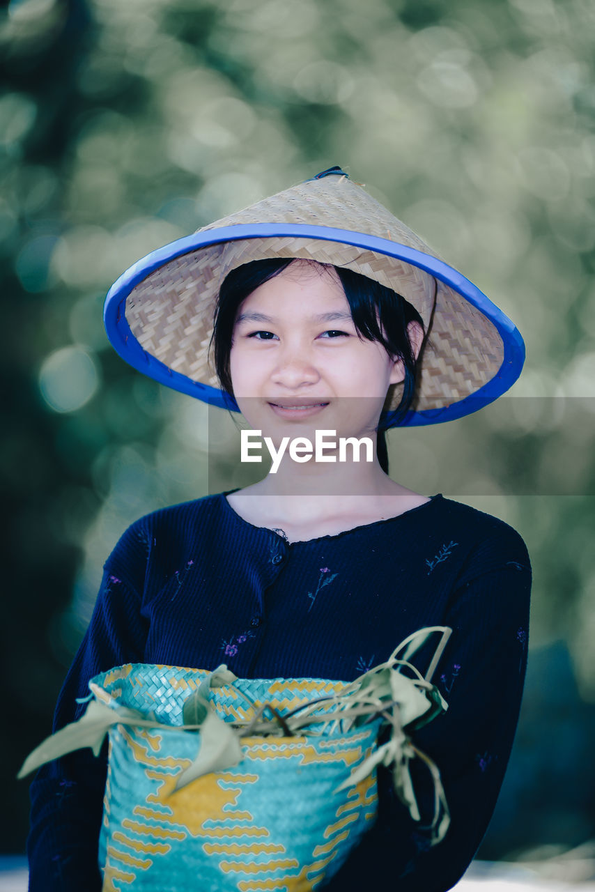 blue, one person, child, childhood, portrait, smiling, clothing, happiness, hat, looking at camera, spring, emotion, front view, female, person, nature, waist up, cute, fashion accessory, costume, standing, outdoors, women, focus on foreground, human face, cheerful, sun hat, innocence, day, traditional clothing