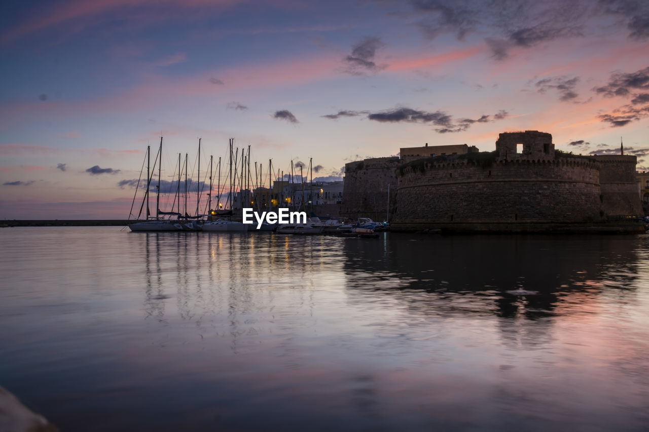 Angevin castle by harbor against sky during sunset