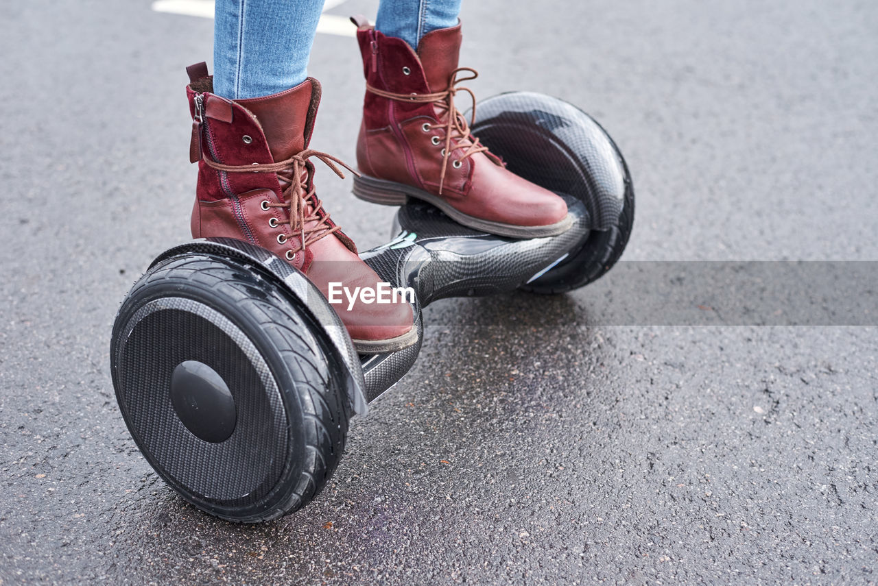 Low section of person standing on hoverboard over road