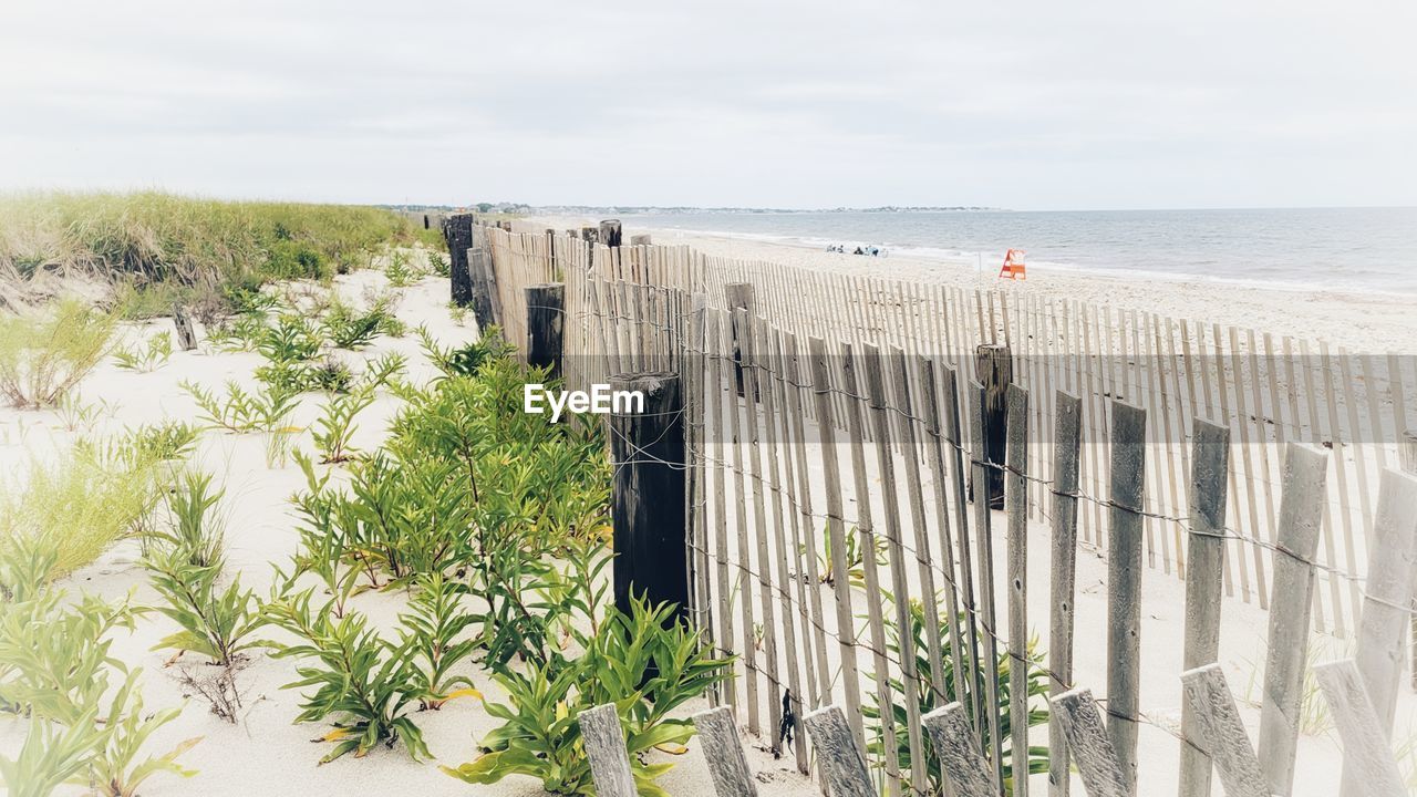 PANORAMIC VIEW OF WOODEN POST ON BEACH AGAINST SKY