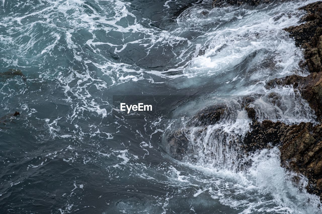 VIEW OF WAVES SPLASHING ON ROCK