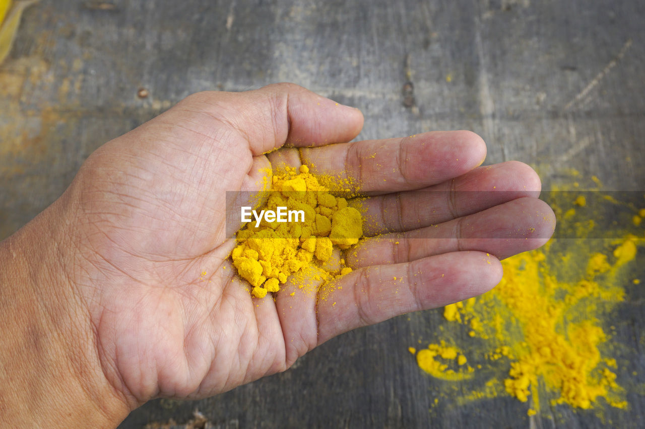 Close-up of hand holding turmeric powder