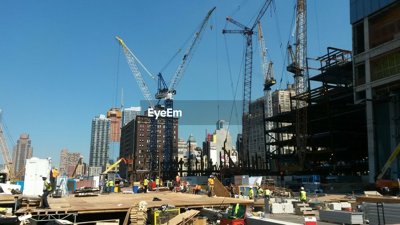 Workers at construction site against clear sky