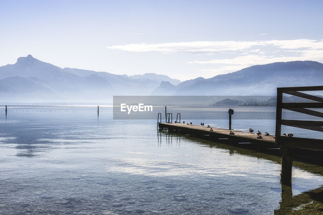 Pier on lake by snowcapped mountains against sky