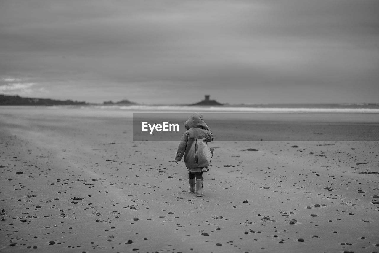 Rear view of girl walking on sand at beach